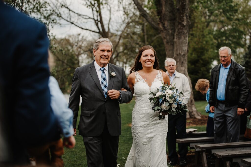 Father of the bride walks the bride down the aisle towards her future husband