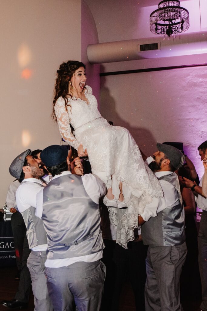 Bride lifted in chair for Hora dance at Legacy Building wedding reception