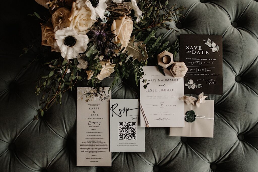 Detail photo of wedding invites, florals, and wedding rings on a couch cushion. 