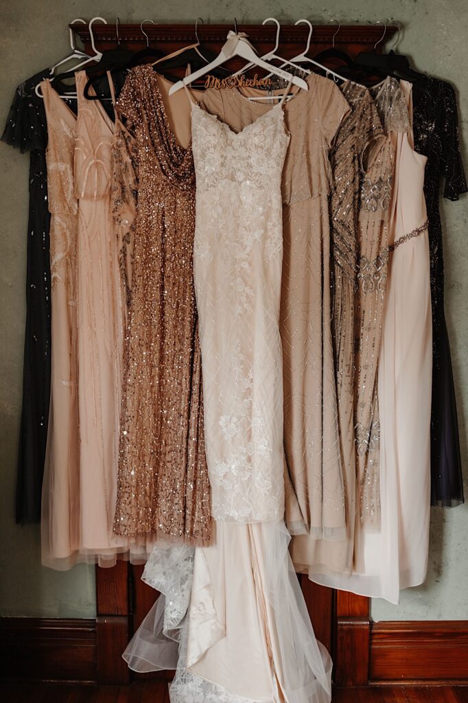 The brides dress and her bridesmaids dresses that are mismatched blush tones with beads hanging on an antique door together.