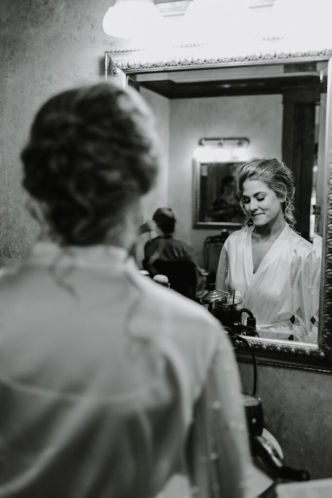 A bride smiles slightly while looking down before putting on her wedding dress the morning of her wedding.