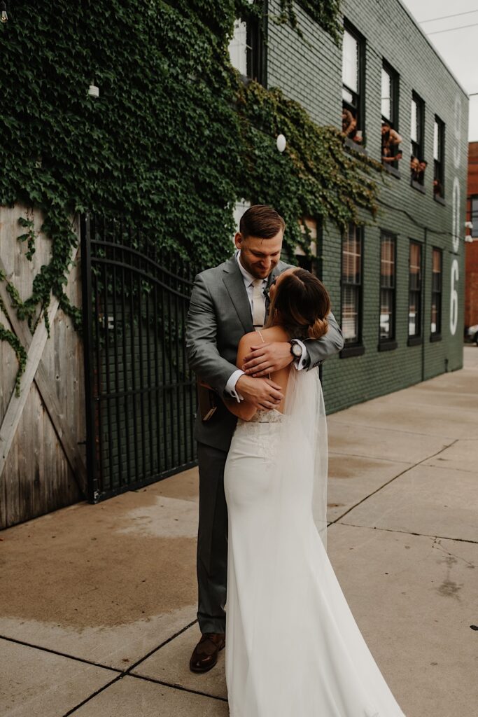 A groom hugs the bride after seeing her for the first time on their wedding day outside their wedding venue.