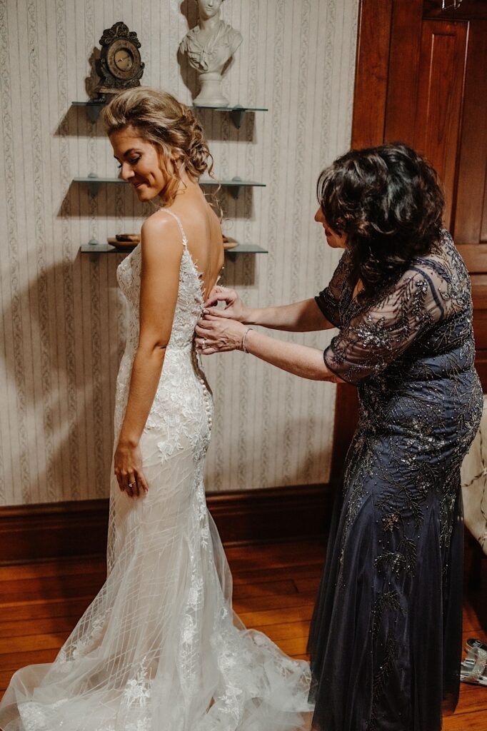 The bride has her mom button the last buttons on her dress the morning of her Chicago wedding.