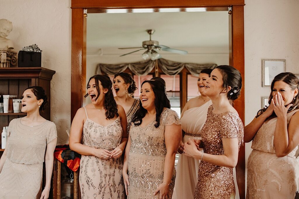The bridesmaids see the bride for the first time and react with smiles and tears.