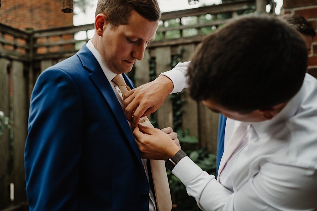 The groom has his best man help him with his tie clip the morning of his wedding in Chicago.