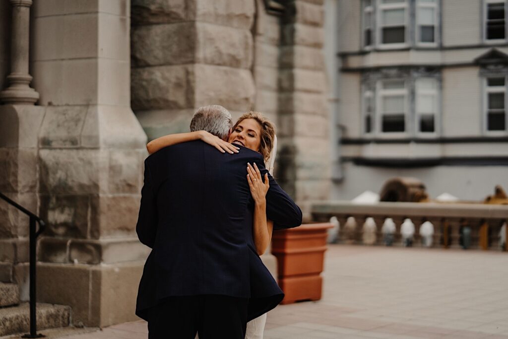 A bride hugs her father after seeing one another for the first time on her wedding day outside of St. Alphonsus Chuch.  