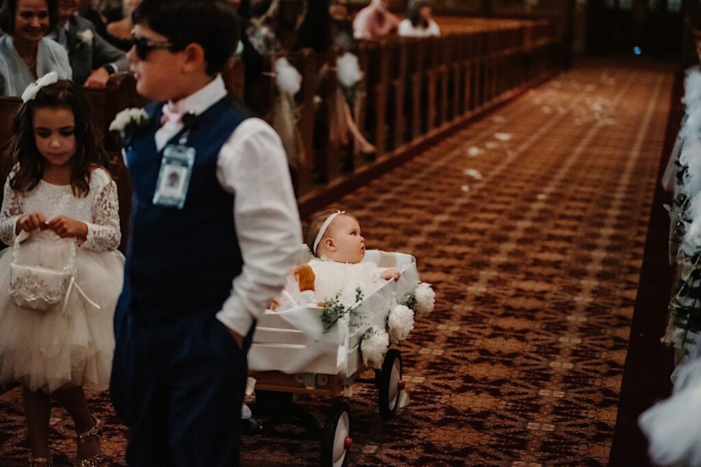 A baby is pulled in a wagon down the long aisle at St Alphonsus chuch in Chicago during a wedding ceremony.