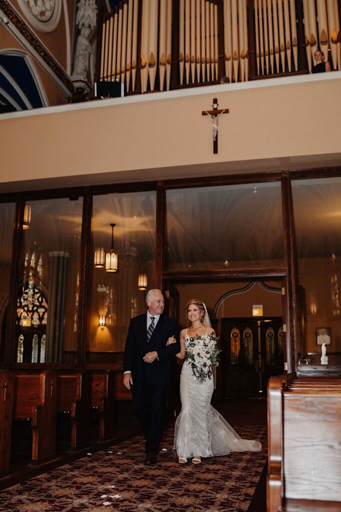 The bride walks down the aisle at St. Alphonsus church in Chicago with her father on her wedding day.