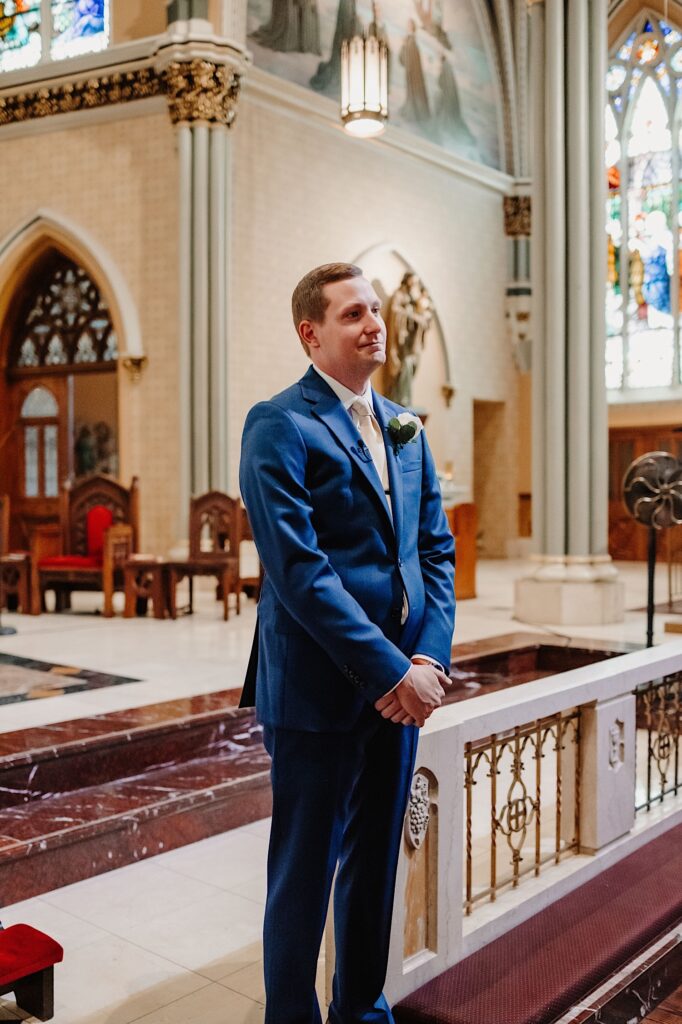 A groom watches his bride approach him as she walks down the aisle on their wedding day.