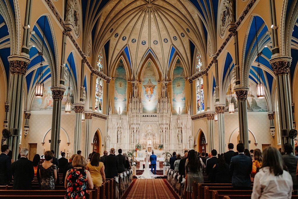 A bride and groom kneel before the altar at their Chicago wedding ceremony at St. Alphonsus church.