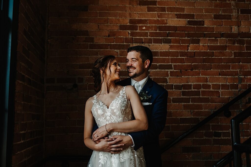 A couple stands holding one another while looking at each other in the stairwell at their Chicagoland wedding venue Salvage One.