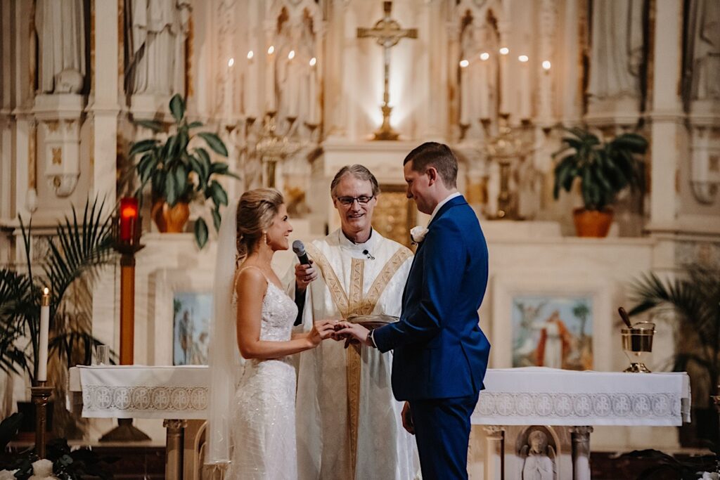 A couple smiles at one another and shares their vows during their ceremony at St. Alphonsus church in Chicago