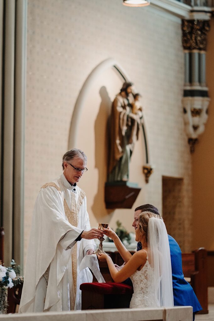 A bride and groom receive communion during their wedding ceremony at St. Alphonsus Church in Chicago