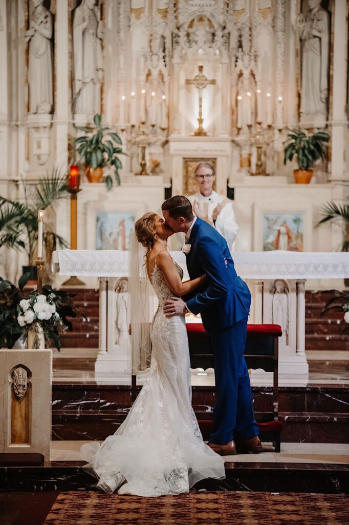 A bride and groom kiss on the alter in front of their family and friends during their wedding ceremony at St Alphonsus Church.