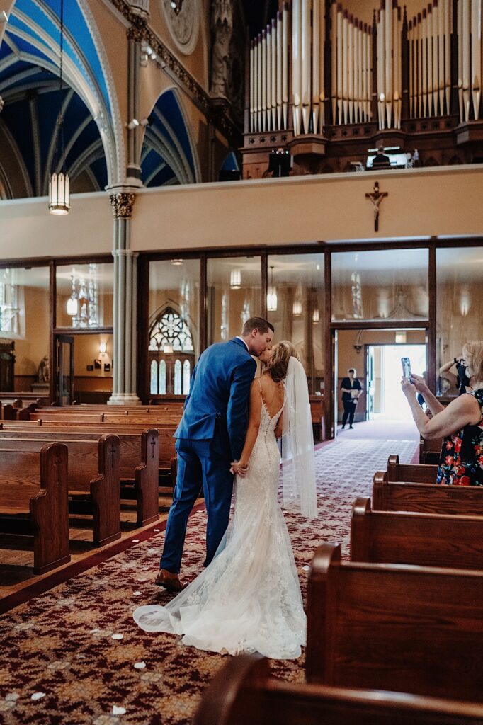 A bride and groom kiss while walking out of their ceremony at St. Alphonsus Church in Chicago