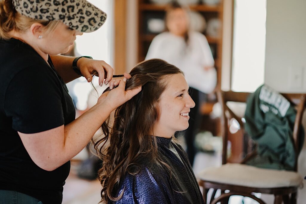 A bridesmaid has her hair curled before the wedding day at their Wisconsin wedding venue.