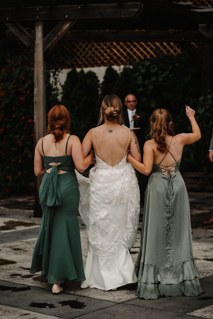 A bride and her bridesmaids walk down the aisle together away from the camera before the wedding ceremony