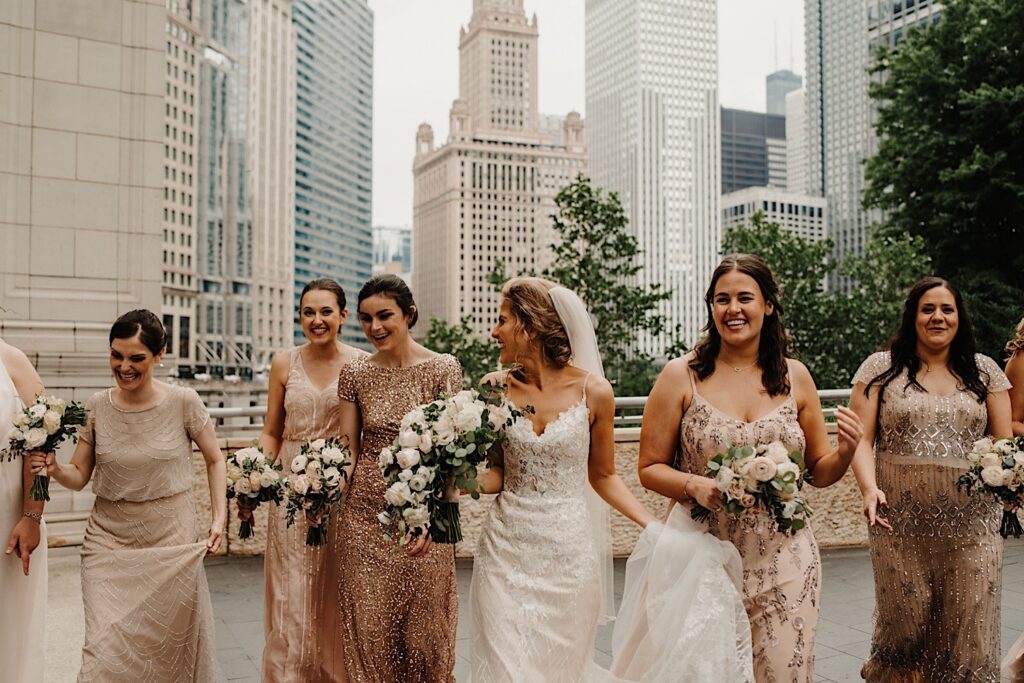 The bride walks towards the camera with her bridesmaids with the tribune tower in the background in Chicago.