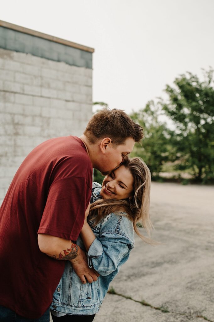 A fiancé kisses his soon to be wife outside of a gas station in Bloomington Normal Illinois during their engagement session.