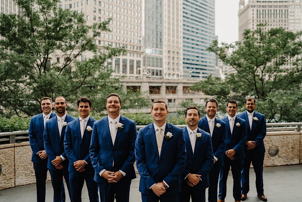 The groom and groomsmen stand in a flying V formation in front of the Chicago Riverwalk.