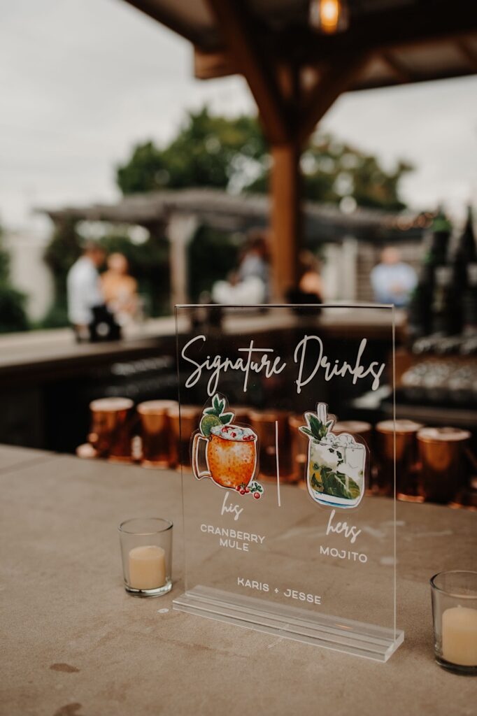 Photo of a sign with signature drinks for a wedding reception and cocktail hour