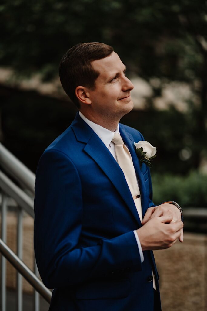 The groom stands in a blue suit admiring his bride during their Chicago wedding portraits