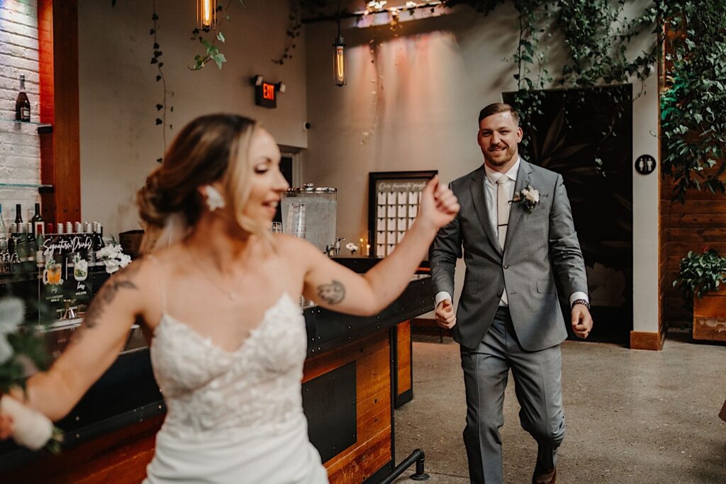 A bride and groom dance as they enter the indoor wedding reception space at Ivy House to celebrate their wedding with their guests.