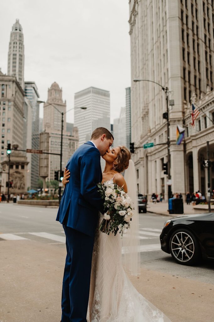 A bride and groom hold hands and kiss while holding one another during their Chicago wedding portraits.