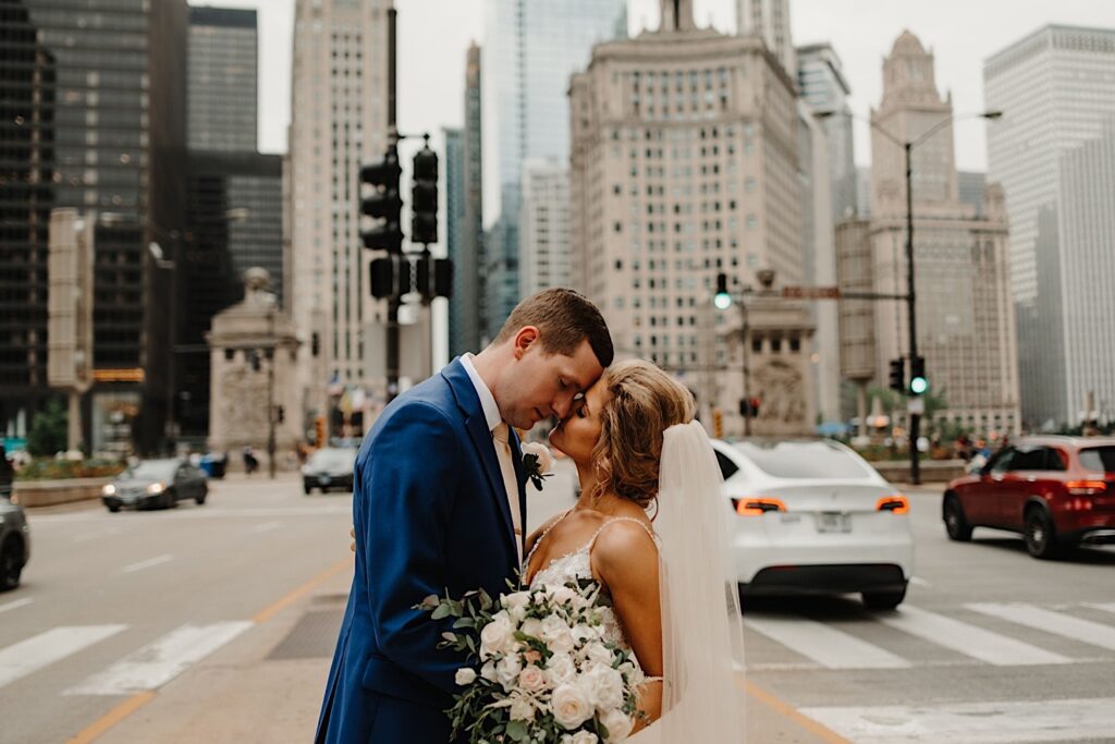 A bride and groom hold each other close while standing in the streets of Chicago, about to kiss during their wedding portraits