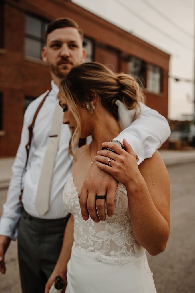 A bride and groom walk down the street together outside of their wedding venue after sneaking away during the reception for some portraits.