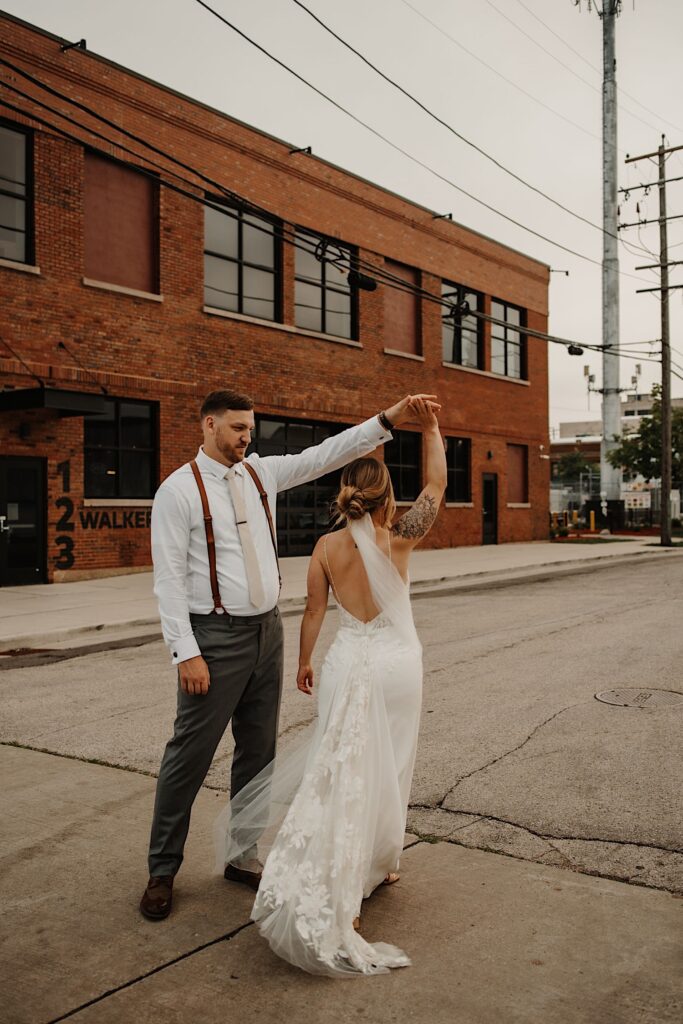 A bride and groom dance in the street together outside of their wedding venue after sneaking away during the reception for some portraits.