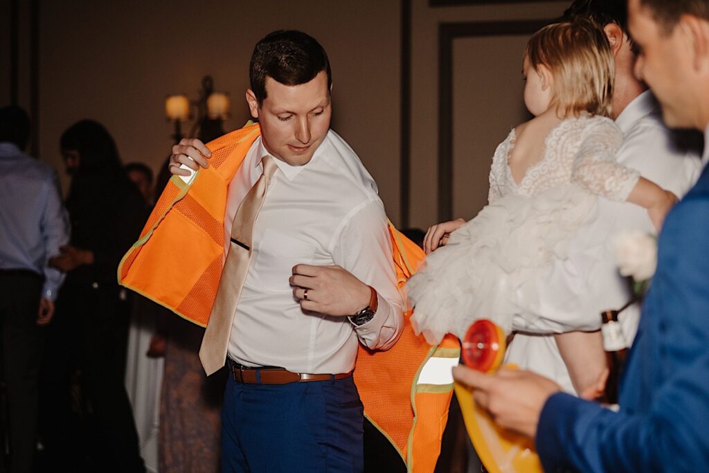 A groom puts on an orange safety vest over her wedding attire during his wedding reception at Salvatore's in Chicago