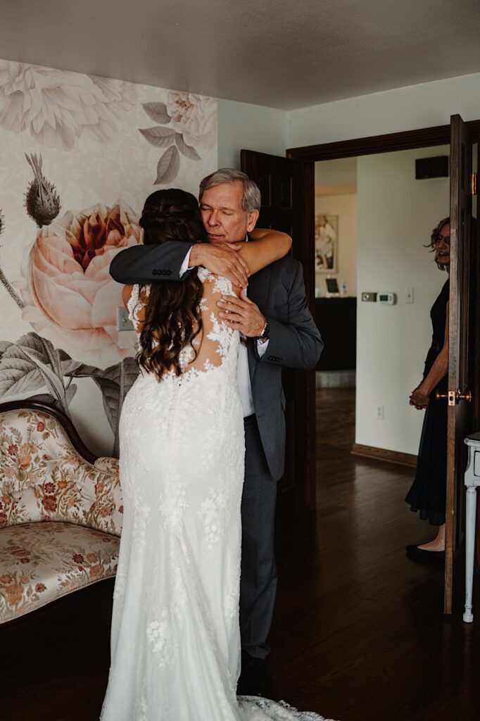 The father of the bride sees his daughter for the first time on her wedding day, and they hug to celebrate.