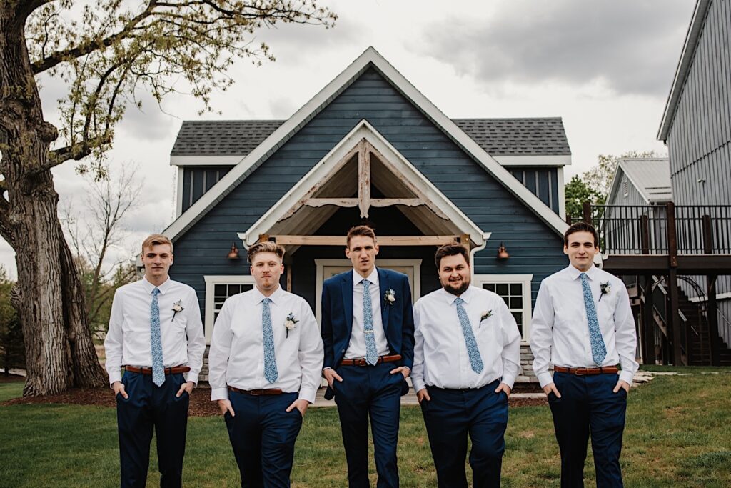 The groom and groomsmen walk towards the camera with their hands in their pockets looking at one another at the grooms Wisconsin wedding.