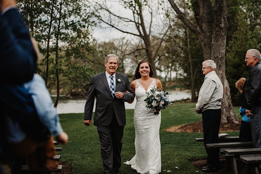 A bride and her father walk down the aisle towards her groom on their wedding day at their Wisconsin wedding venue 1841 Farms and Vineyard