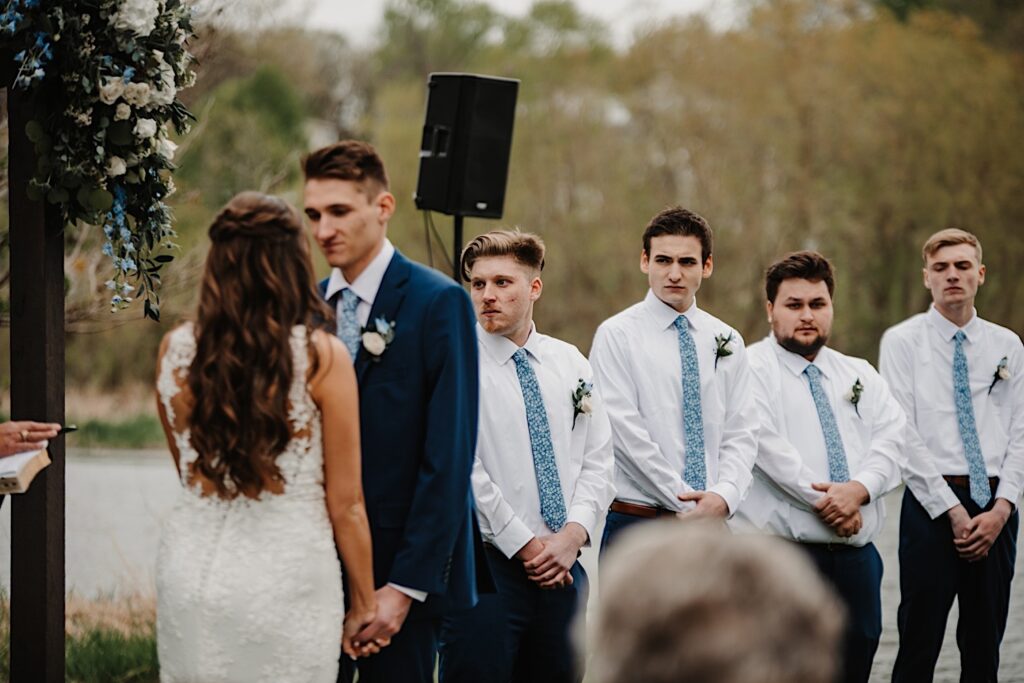 The groomsmen stand and watch their best friend get married during their ceremony at their Wisconsin wedding venue.