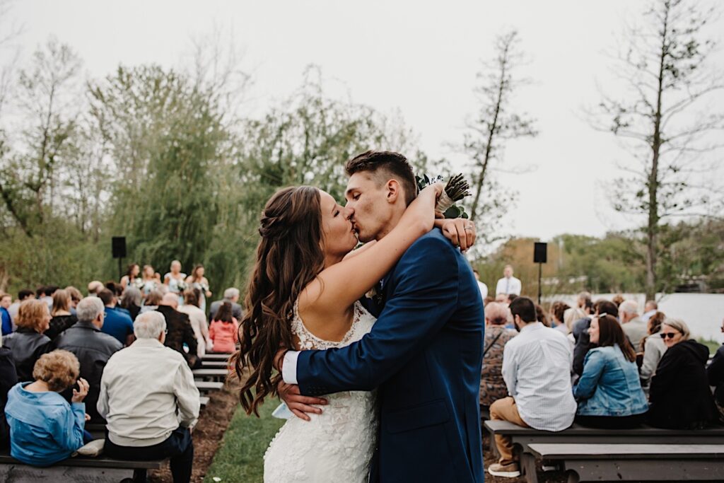 A bride and groom kiss after their outdoor wedding ceremony at their Wisconsin wedding venue.