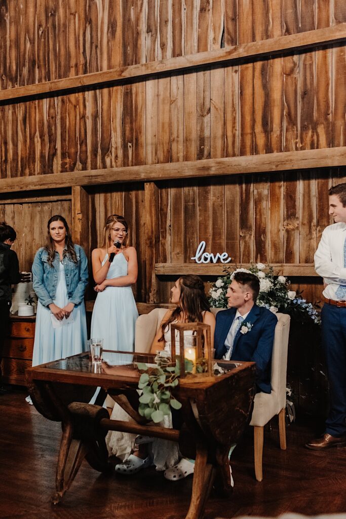 A bridesmaid gives a toast to the newly weds in a barn wedding venue.