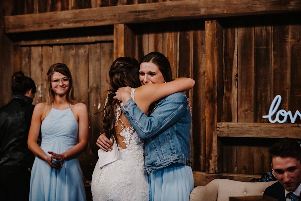 A bride hugs her sister and bridesmaid after she gave a toast to the newly weds at their Wisconsin wedding.