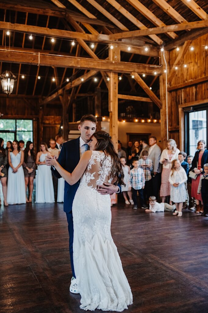 A bride and groom hold each other tight while dancing at their wedding venue.