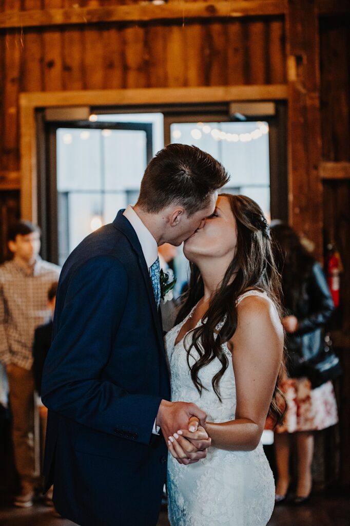 A bride and groom kiss in their barn wedding venue in Wisconsin.