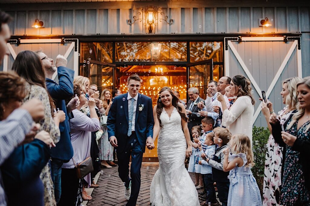 A bride and groom have a bubble exit surrounded by their loved ones while leaving their reception at their Wisconsin wedding venue.