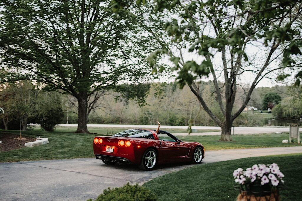 The bride and groom drive away from their Wisconsin wedding day in a red sports car.