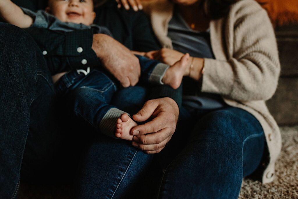 Closeup of a family sitting together wearing matching jeans, the baby is smiling at the camera.