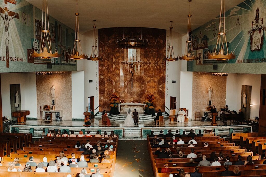 A bride and groom kneel at the altar at Christ the King Church during their fall wedding ceremony in Chicago