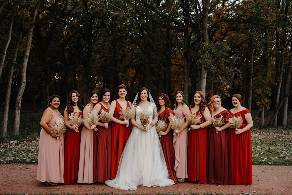 A bride stands with her bridesmaids on either side of her as they all smile at the camera with the fall leaves of Chicago behind them