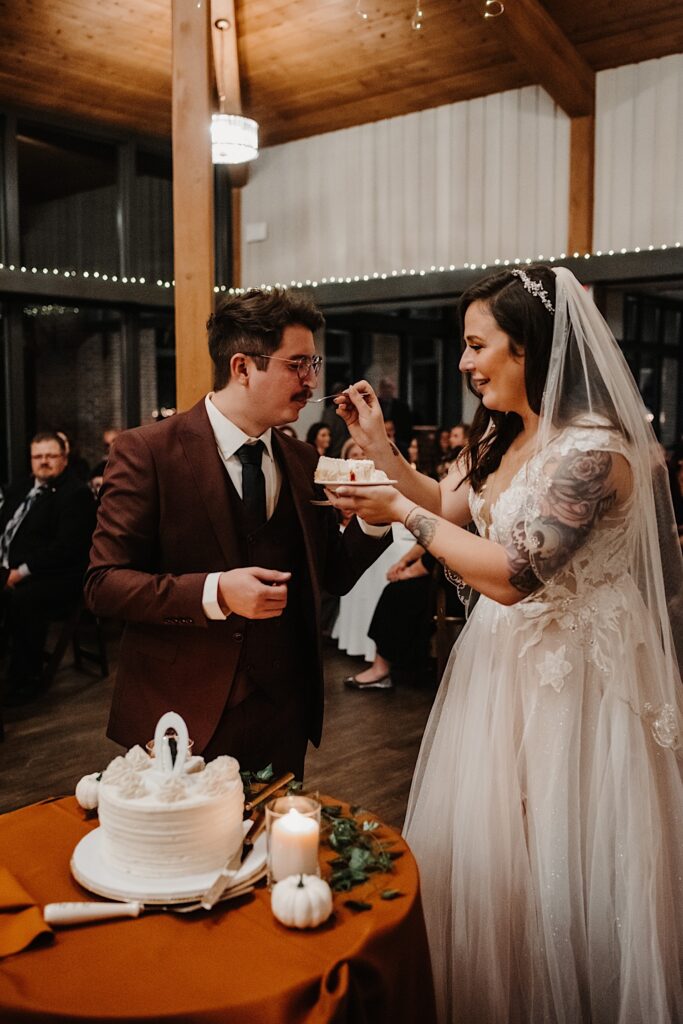 A bride feeds a piece of the wedding cake to the groom during their wedding reception at the Oakbrook Bath and Tennis Club