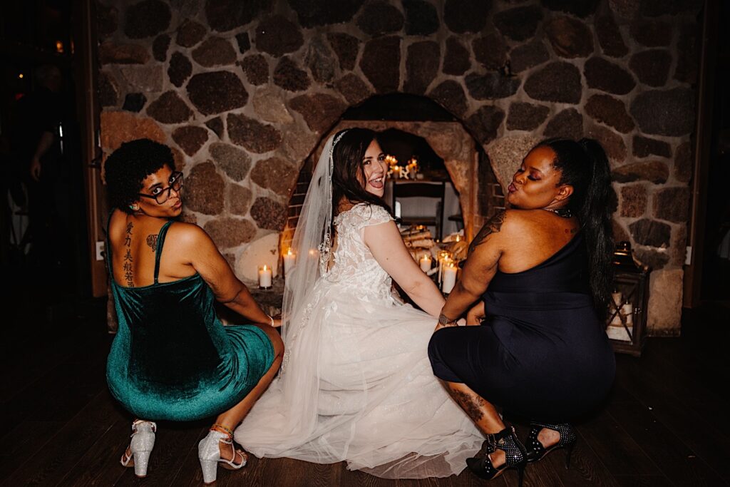 A bride dances with her friends on either side of her during a wedding reception