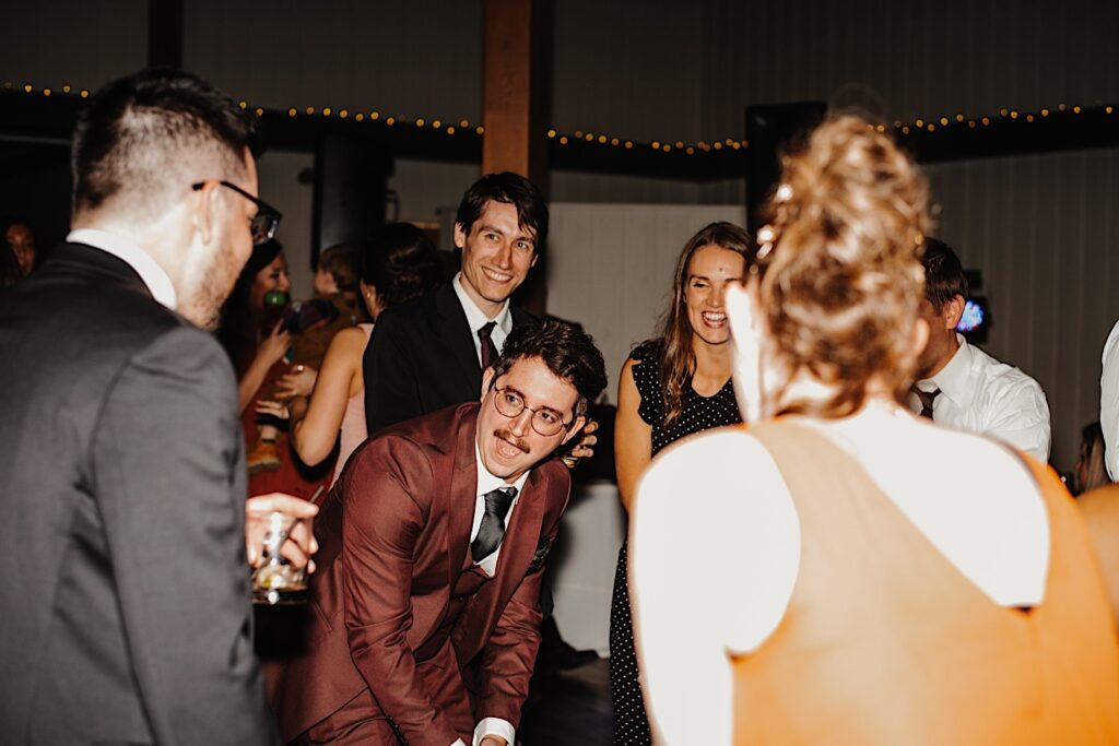 A groom celebrates with the guests of his fall wedding in Chicago at their reception space, Oakbrook Bath and Tennis Club