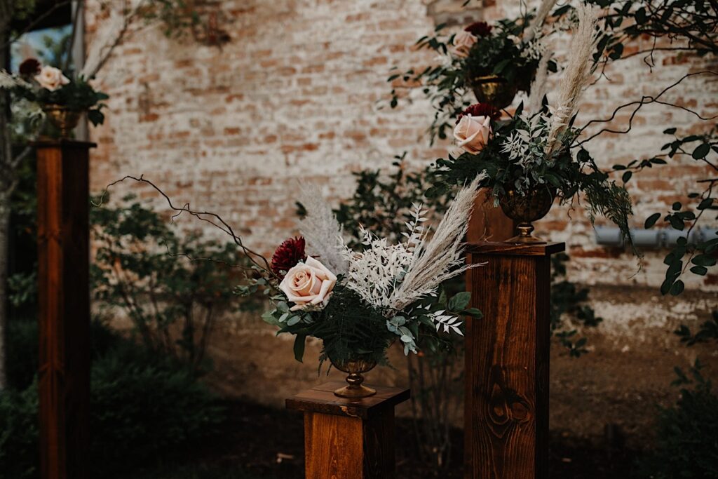 Floral decorations set up in front of a brick wall as part of a wedding ceremony space